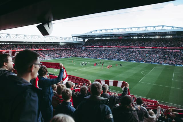 Football supporters raising scarves in a packed stadium
